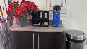 A kitchenette area with a coffee machine, a trash bin, and a potted plant. - Travelodge by Wyndham Vernon CT (Vernon)