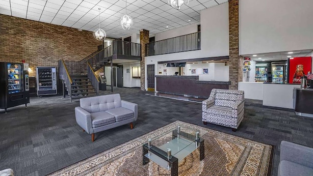 A spacious lobby with a high ceiling, a staircase, a reception desk, and seating areas. - Travelodge by Wyndham Vernon CT (Vernon)