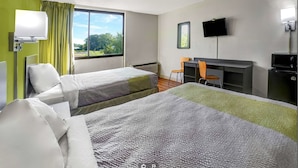 A hotel room with two beds, a desk, a chair, a TV, and a window with a view of trees. - Travelodge by Wyndham Vernon CT (Vernon)