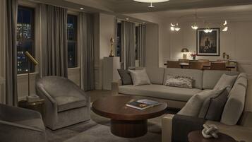 A modern living room with a sofa, armchairs, a coffee table, and a dining area with a chandelier.