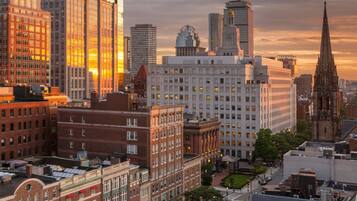 A cityscape with a mix of modern and historic buildings, including a prominent clock tower and a tall glass skyscraper.