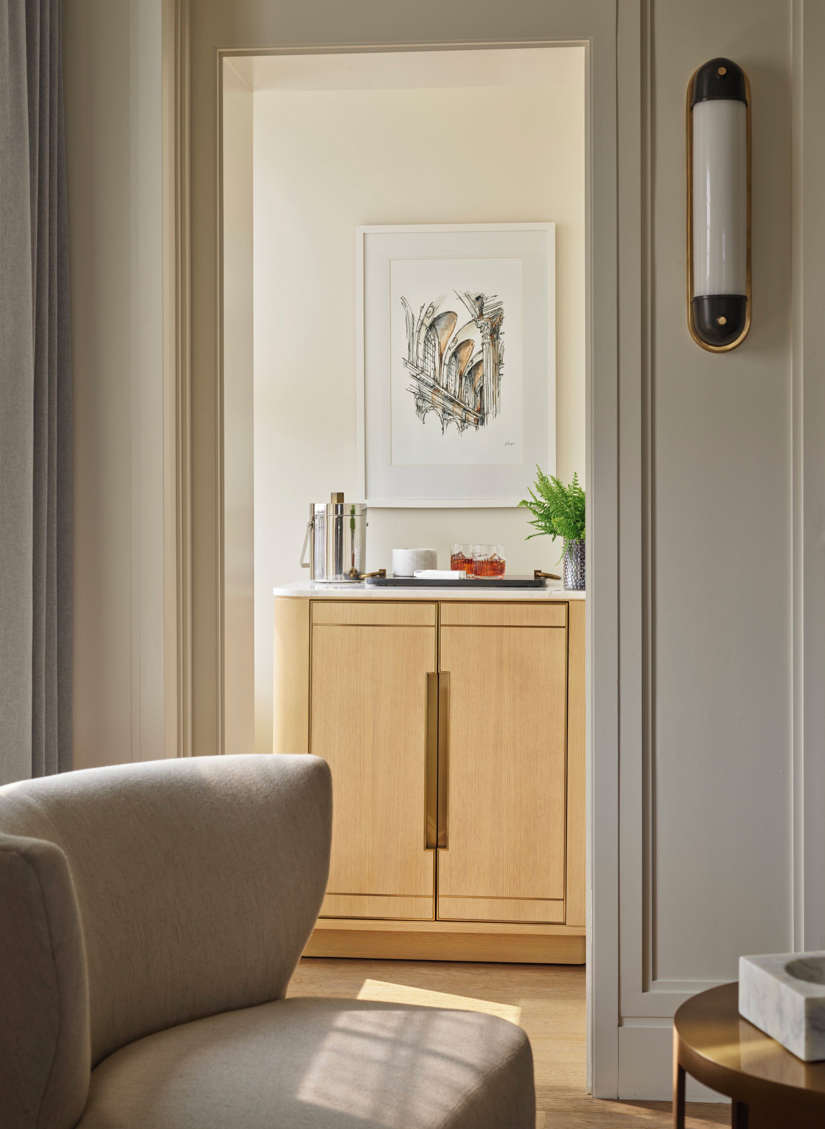 Un intérieur moderne avec un meuble en bois, une œuvre d’art encadrée et une petite table sur laquelle est posée une plante.