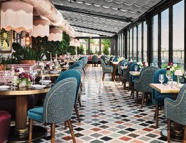 A restaurant with a long dining area, multiple tables, and chairs.