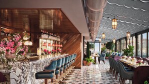 A bar area with marble countertops, blue bar stools, and a variety of bottles. - The Newbury Boston (Boston)