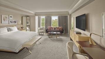A hotel room with a large bed, a sofa, a desk, and a TV.