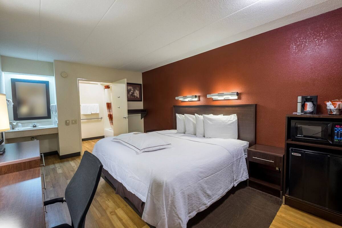 Ein Hotelzimmer mit Bett, Schreibtisch, Stuhl und einer Küchenzeile.