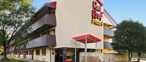 A Red Roof Plus hotel with a two-story structure, a visible lobby, and a parking area.