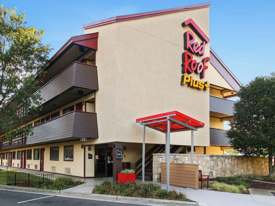 A Red Roof Plus hotel with a two-story structure, a visible lobby, and a parking area.