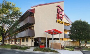 A Red Roof Plus hotel with a two-story structure, a visible lobby, and a parking area.