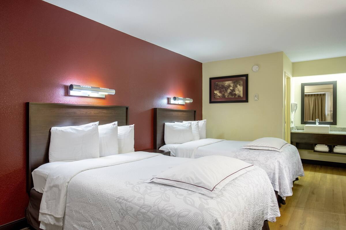 Ein Hotelzimmer mit zwei Betten, einem großen Spiegel und Holzboden.