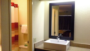 Une salle de bain avec un lavabo blanc, un miroir et des toilettes.