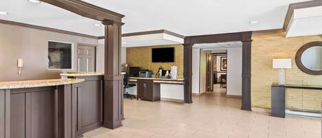 Un moderno vestíbulo de hotel con una recepción, una zona de bar y un espacio para sentarse.