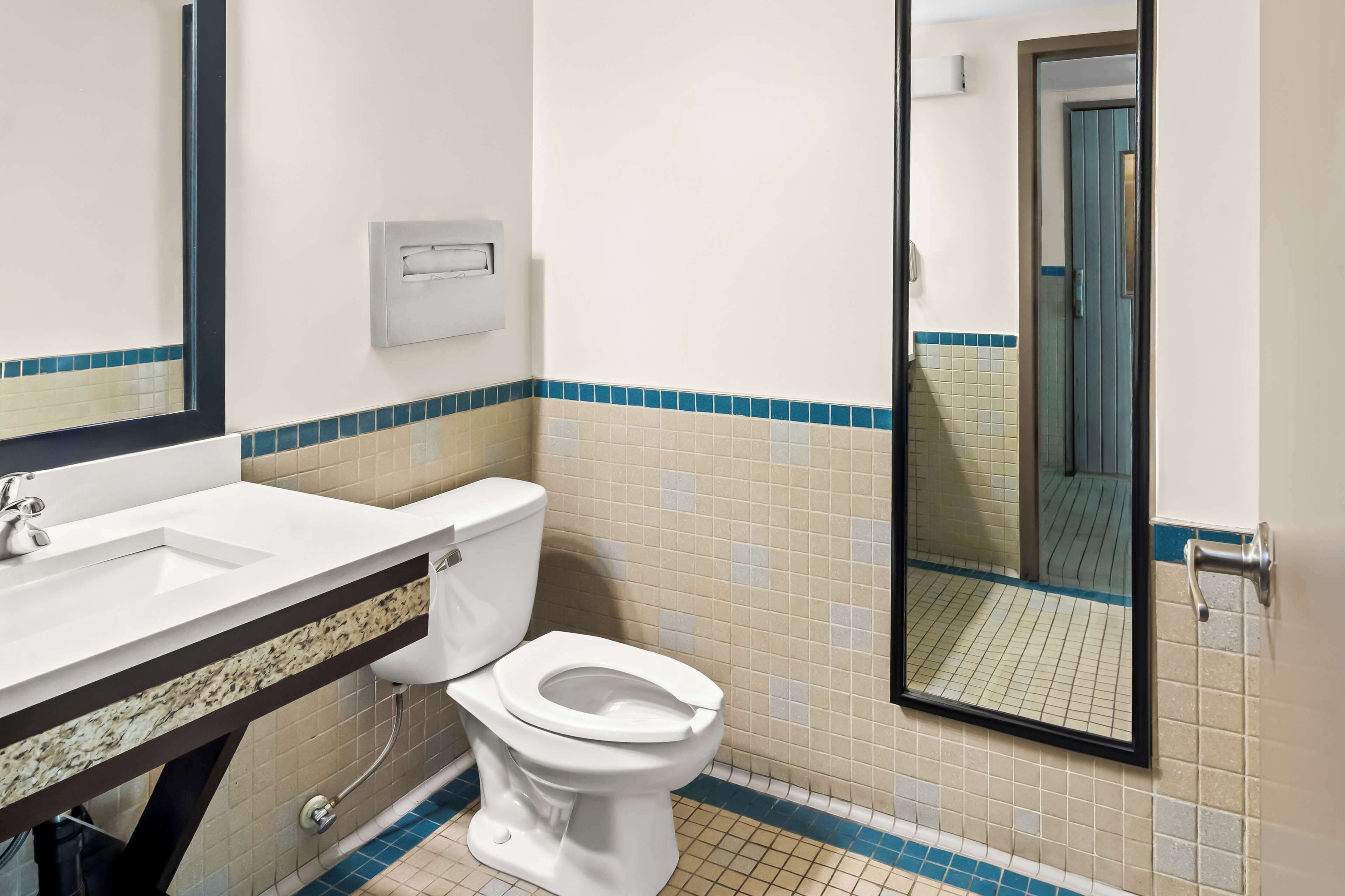 Un baño con lavamanos, inodoro y espejo blancos.