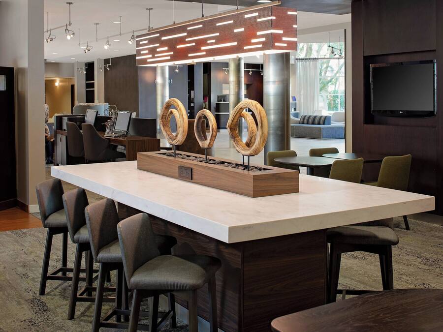 Uma área de bar moderna com uma ilha grande, banquetas e uma peça central de madeira original.