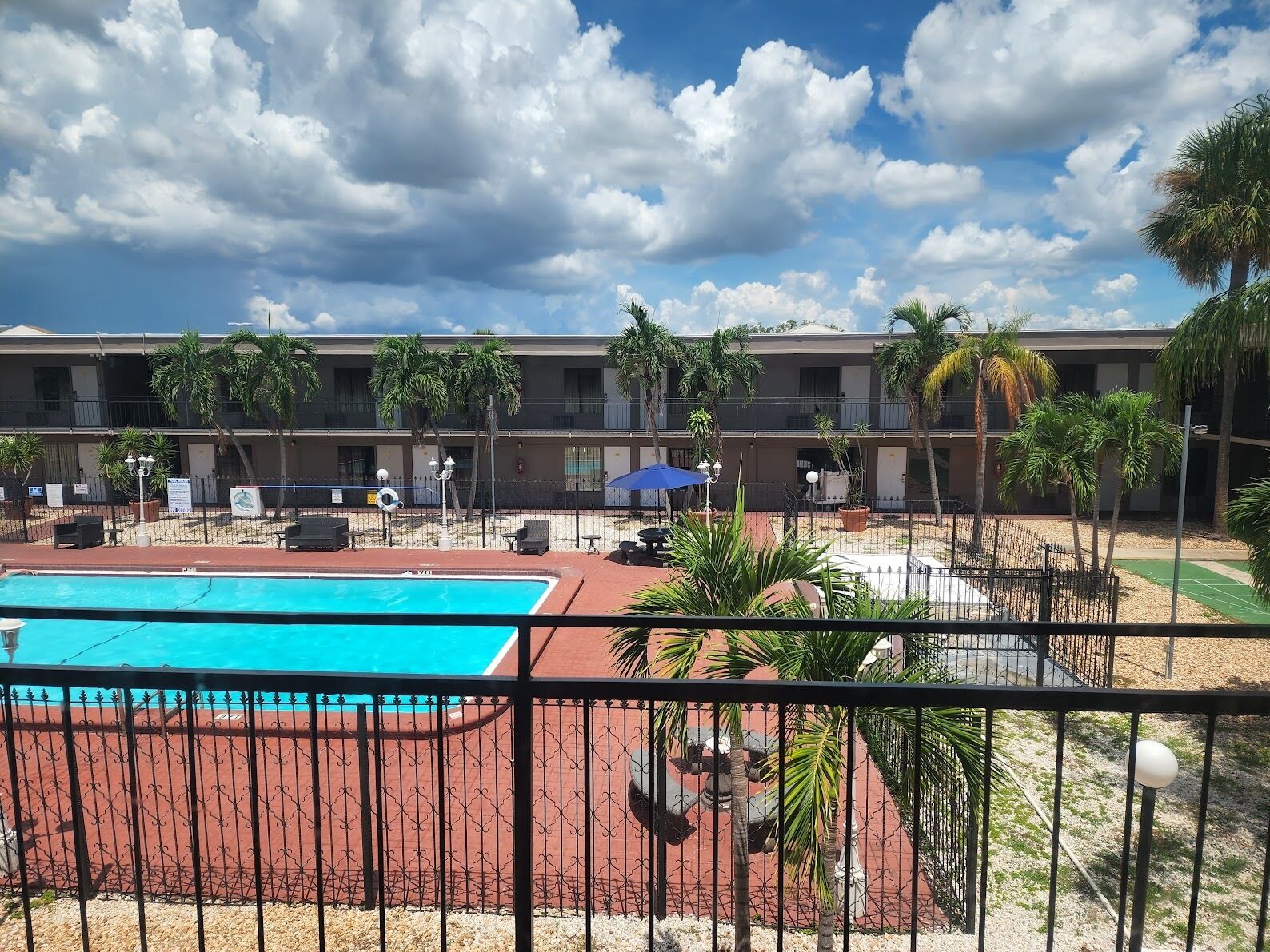Un hôtel doté d’une piscine, d’un espace extérieur aménagé et de palmiers.