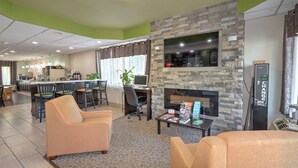 A hotel lobby with a fireplace, seating area, and a kitchenette in the background. - Super 8 by Wyndham Knoxville West/Farragut (Knoxville)
