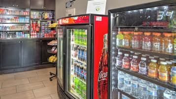 A convenience store with refrigerated beverage dispensers, shelves stocked with snacks, and a Coca-Cola branded refrigerator.