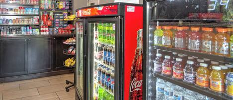 Een gemakswinkel met gekoelde drankautomaten, schappen vol snacks en een koelkast met Coca-Cola branding.