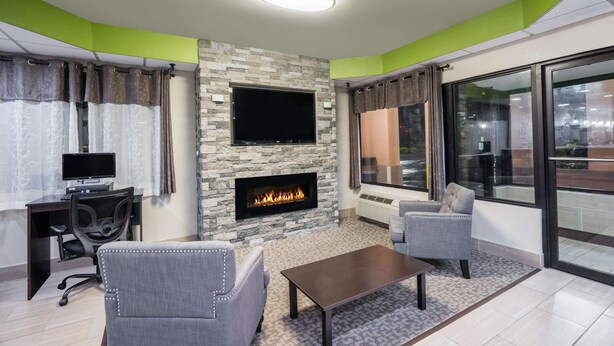 A modern living room with a stone fireplace, a flat-screen TV, and comfortable seating. - Super 8 by Wyndham Knoxville West/Farragut (Knoxville)