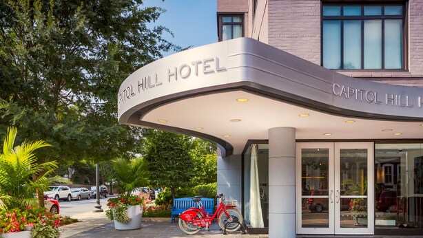 The exterior of Capitol Hill Hotel with a modern design, featuring a curved entrance and a red bicycle parked outside. - Capitol Hill Hotel (Washington)