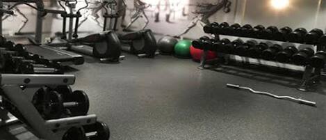 Une salle de sport équipée de tapis de course, de vélos d’appartement et de divers poids.