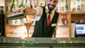 Un barman verse une boisson dans un verre à martini.
