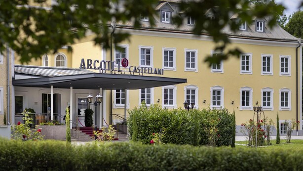 Un bâtiment jaune avec l’enseigne « ARCOTEL CASTELAN » et une entrée abritée.