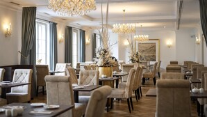 Un vaste espace dédié à la salle à manger, avec de nombreuses tables et chaises, de magnifiques lustres et des vases décoratifs.