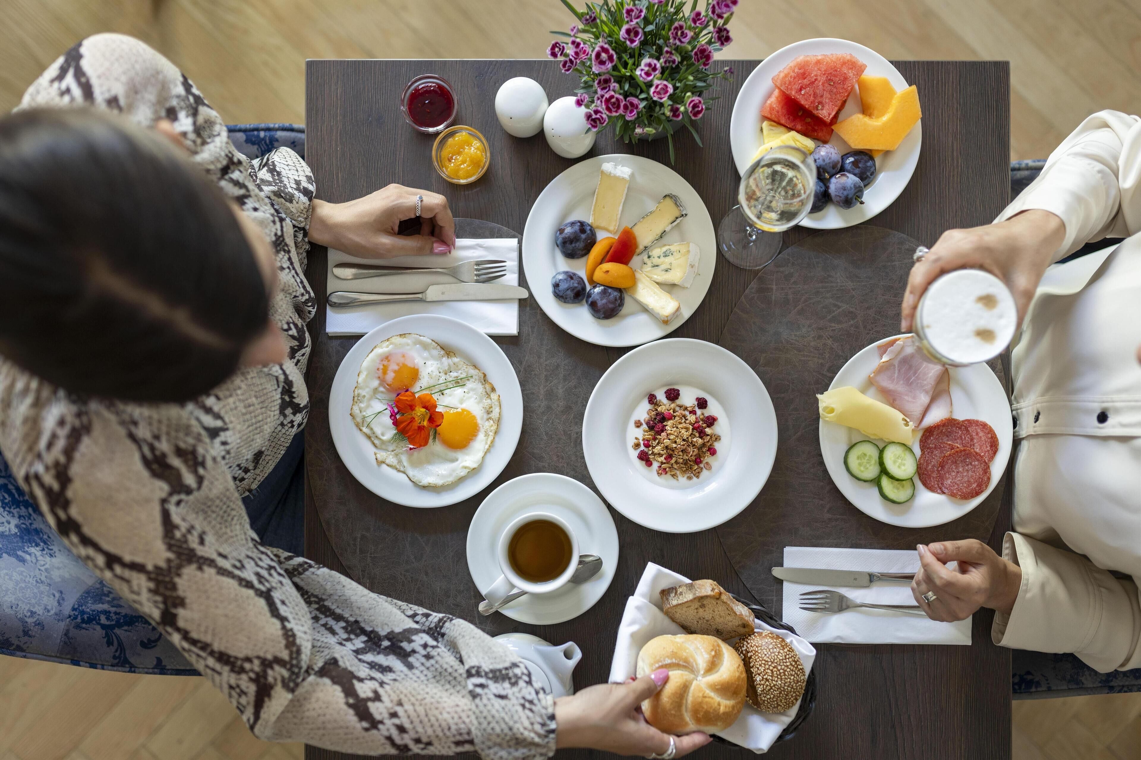 Une table dressée pour le petit-déjeuner, avec différents plats, notamment des œufs, des fruits, du fromage et du pain.