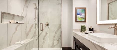 A modern bathroom with a glass-enclosed shower, a double sink vanity, and a marble backsplash.