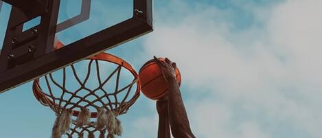 A basketball hoop with a net and a basketball in mid-air, against a clear sky.