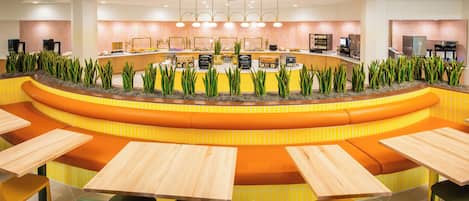 A modern restaurant with a curved counter, multiple seating areas, and a variety of appliances and decor.