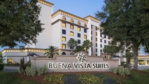 Egy „BUENA VISTA SUITES” felirattal ellátott hotelszign és egy többemeletes, számos ablakkal rendelkező épület.