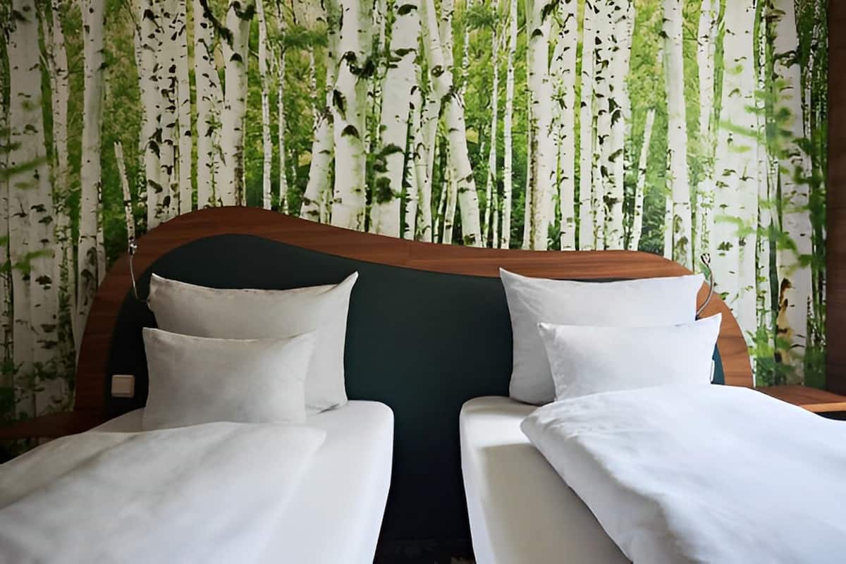 A hotel room with two beds, a wooden headboard, and a wall with a vertical garden design.
