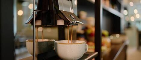 A coffee machine dispensing coffee into two cups.