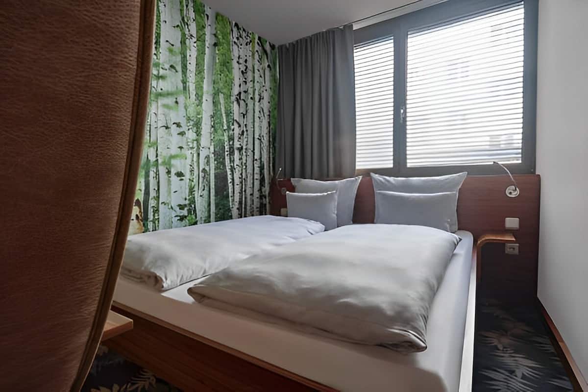 A hotel room with a bed, curtains, and a window.