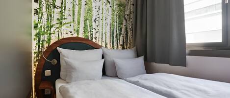 Un dormitorio con cama, cabecera y ventana con cortinas.