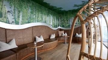 Ein moderner Lounge-Bereich mit gebogenen Sitzgelegenheiten, einer Wandmalerei und einem Hängekorbsessel.