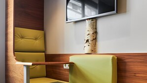 Un interior moderno con un banco curvo de madera, un televisor de pantalla plana montado y un tronco de abedul como elemento decorativo.