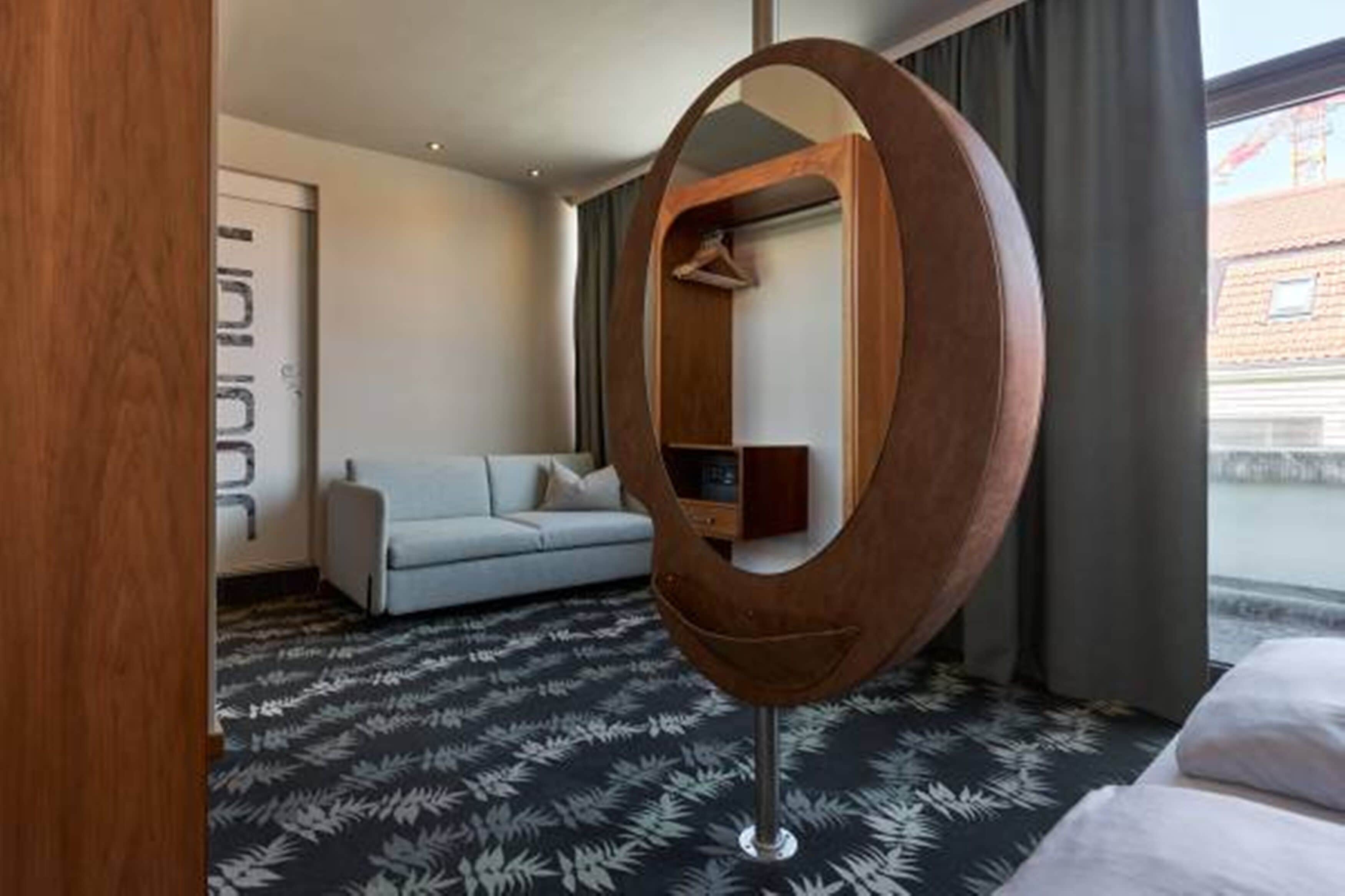 Een hotelkamer met een grote spiegel, een bank, een bed en uitzicht.