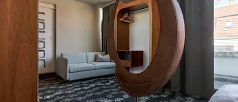 A hotel room with a large mirror, a sofa, a bed, and a view of the outside.