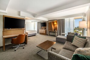 A modern hotel room with a flat-screen TV, a desk, a comfortable sofa, and a bed. - Holiday Inn Oxnard – Ventura by IHG (Oxnard)