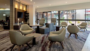 A modern lounge area with sofas, armchairs, and a flat-screen TV mounted on the wall. - Holiday Inn Oxnard – Ventura by IHG (Oxnard)