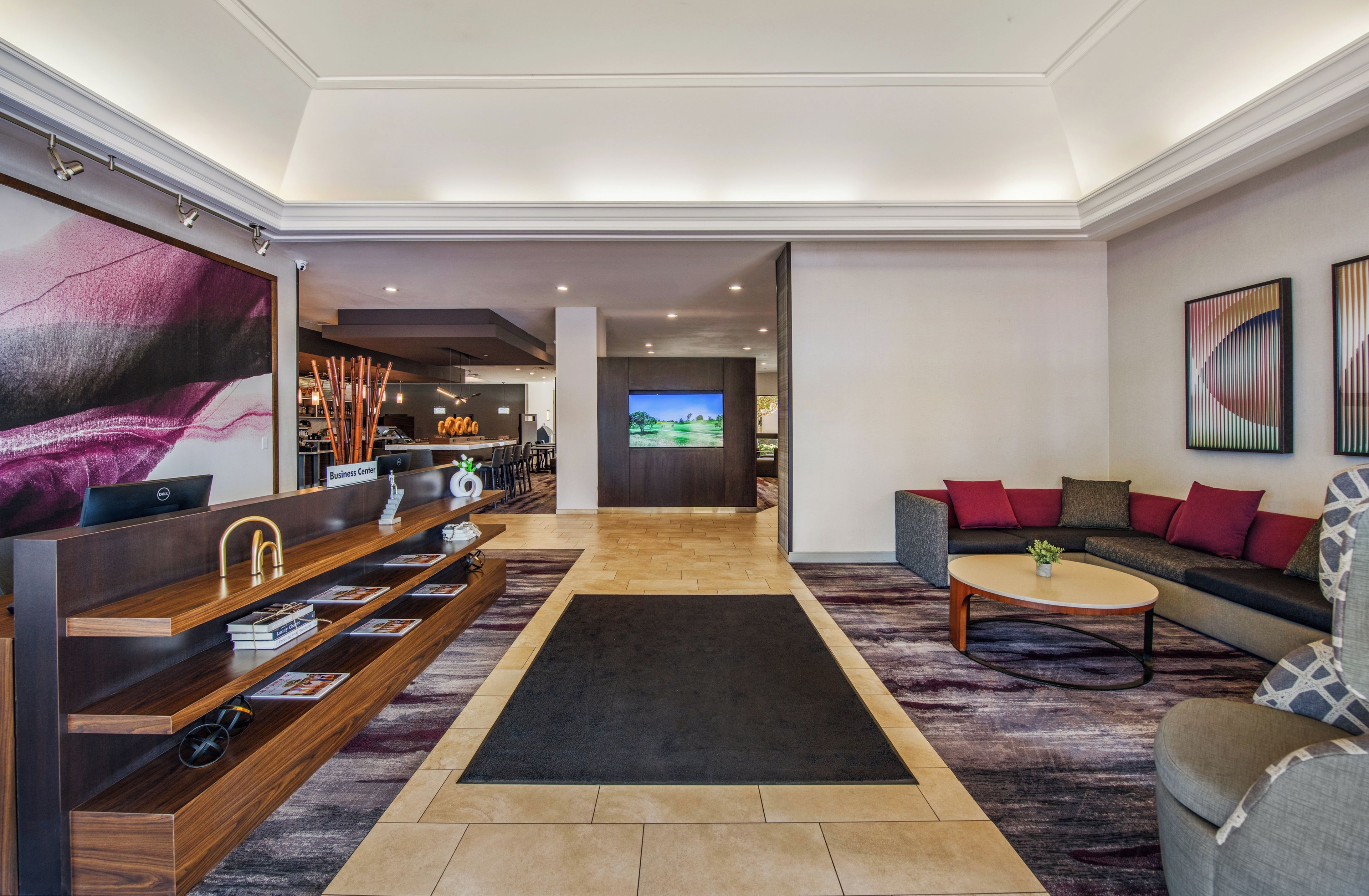 Un vestíbulo amplio con una mesa de recepción, un sofá, una mesa de centro y una pantalla de televisión.