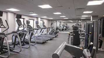 Une salle de sport équipée de tapis de course, de vélos elliptiques et d’appareils de musculation.
