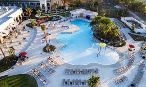 Vista aerea di un resort con una grande piscina, lettini e palme.