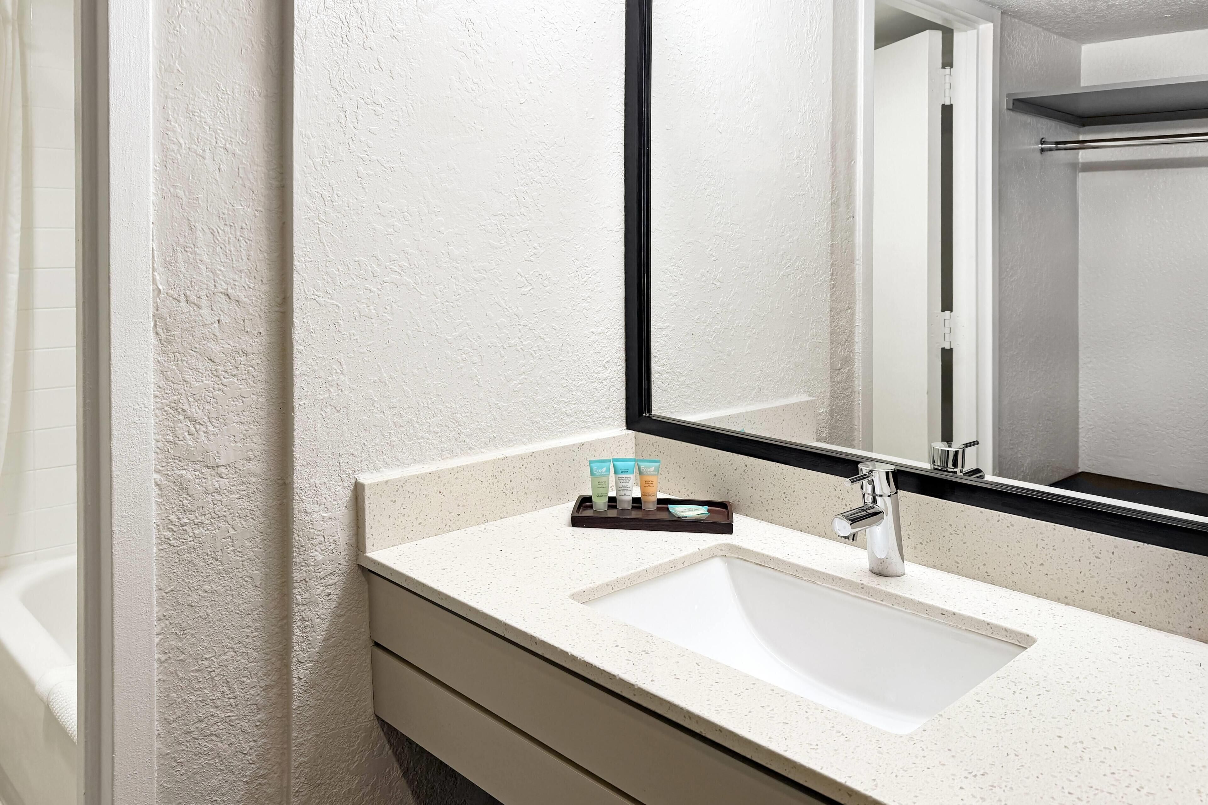 A bathroom with a white sink, a mirror, and a towel rack.