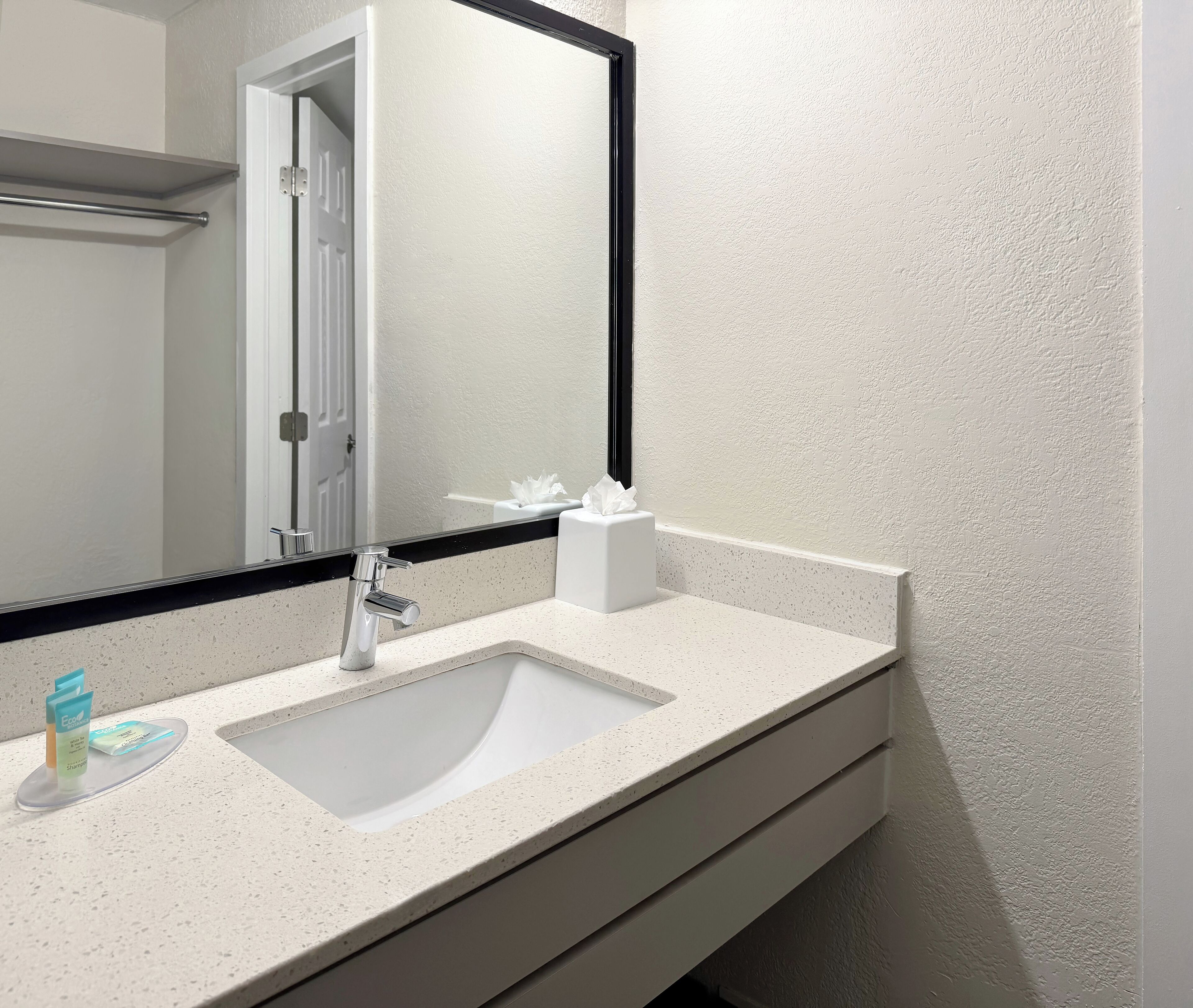 Un baño con un lavamanos blanco, un espejo y un dispensador de toallas.