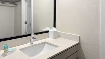 Un baño con un lavamanos blanco, un espejo y un dispensador de toallas.