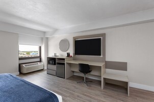 Una habitación de hotel moderna con cama, escritorio, silla, calefactor, ventana y vista a la ciudad.